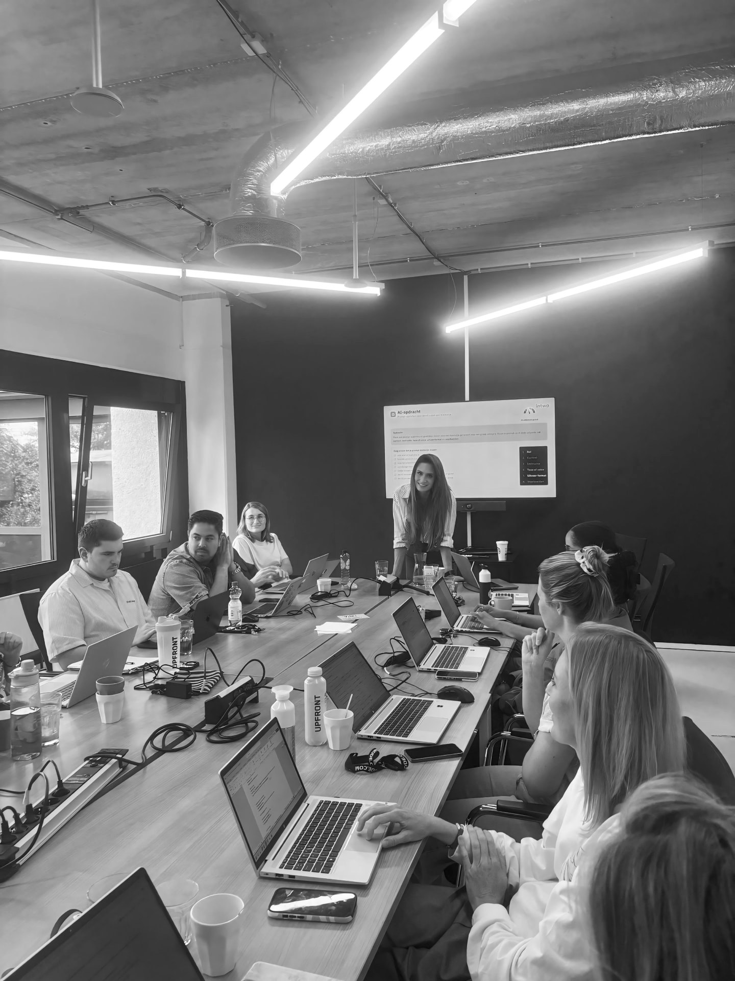 Danique geeft een AI-training aan een groep professionals die achter hun laptops meewerken